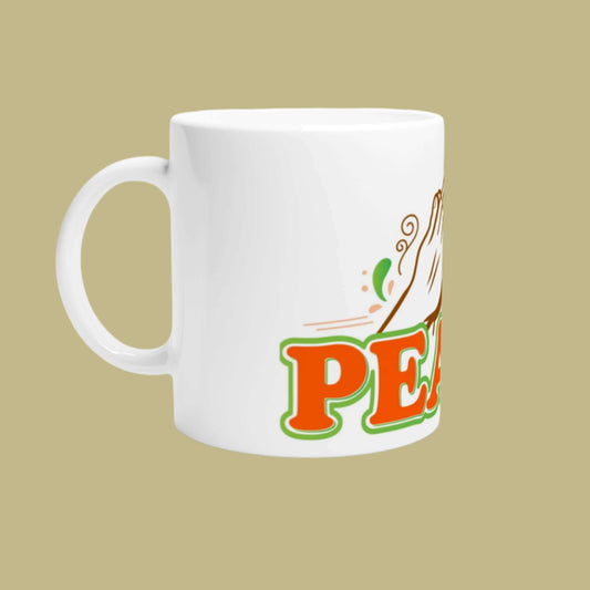 White ceramic cup with the hand claps in prayer and the word peace written in burnt orange and green